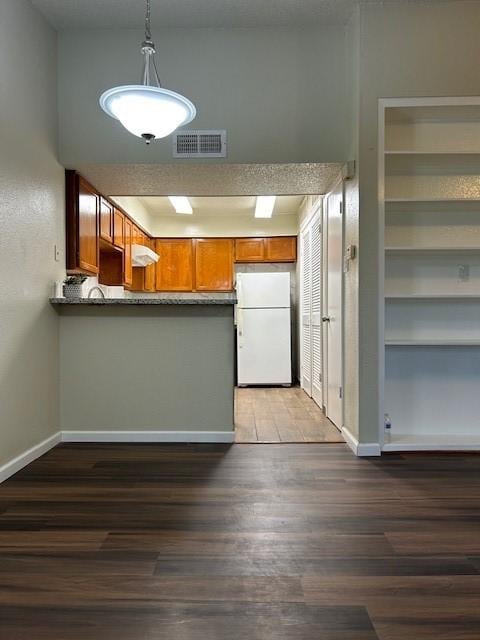 10555 Turtlewood Ct Unit 2111, Houston, TX 77072 - kitchen featuring freestanding refrigerator, a peninsula, brown cabinets, wood finished floors, and hanging light fixtures