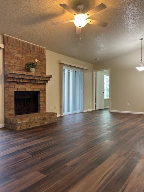10555 Turtlewood Ct Unit 2111, Houston, TX 77072 - unfurnished living room featuring a textured ceiling, dark wood-type flooring, ceiling fan, and a fireplace
