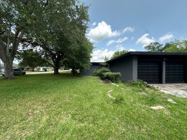 3900 Aggie Dr, Bay City, TX 77414 - view of green lawn featuring a garage and driveway