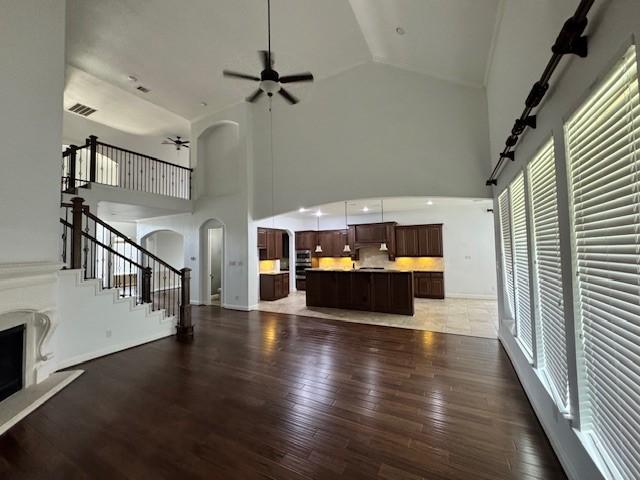 12911 Long Hunter Ct, Humble, TX 77346 - unfurnished living room with arched walkways, plenty of natural light, ceiling fan, high vaulted ceiling, and a fireplace with raised hearth