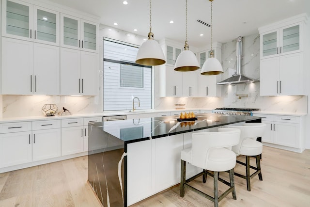 1022 Allston St, Houston, TX 77008 - kitchen featuring wall chimney range hood, tasteful backsplash, light wood-style flooring, a center island, and a breakfast bar