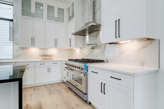 1022 Allston St, Houston, TX 77008 - kitchen featuring range with two ovens, wall chimney range hood, light wood finished floors, white cabinets, and light stone countertops