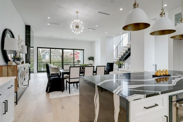 1022 Allston St, Houston, TX 77008 - kitchen with light wood finished floors, wall oven, a chandelier, white cabinets, and stone countertops