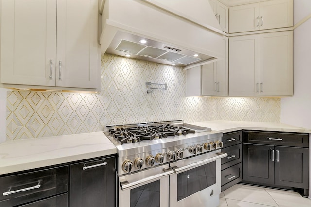 19303 Tree Canopy Ct, Cypress, TX 77433 - kitchen featuring range with two ovens, light stone countertops, tasteful backsplash, light tile patterned flooring, and ventilation hood
