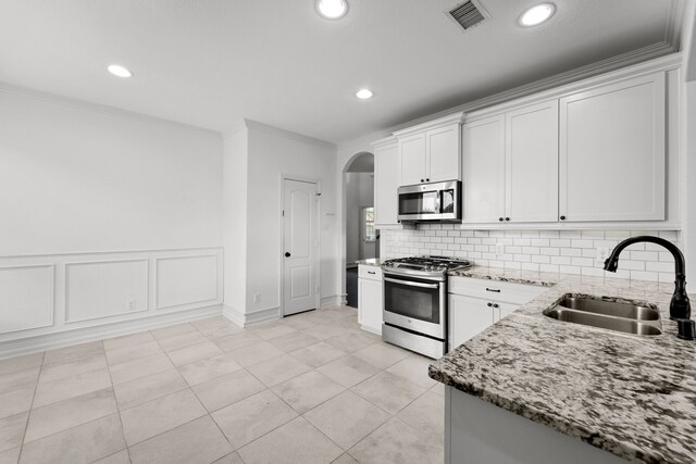 16746 Highland Country Dr, Cypress, TX 77433 - kitchen featuring stainless steel appliances, arched walkways, light stone countertops, decorative backsplash, and white cabinets
