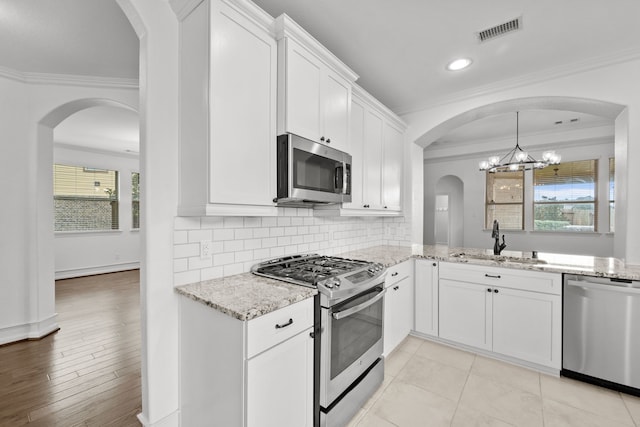 16746 Highland Country Dr, Cypress, TX 77433 - kitchen featuring appliances with stainless steel finishes, ornamental molding, light stone counters, backsplash, and white cabinetry