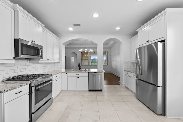 16746 Highland Country Dr, Cypress, TX 77433 - kitchen featuring stainless steel appliances, crown molding, arched walkways, white cabinetry, and tasteful backsplash