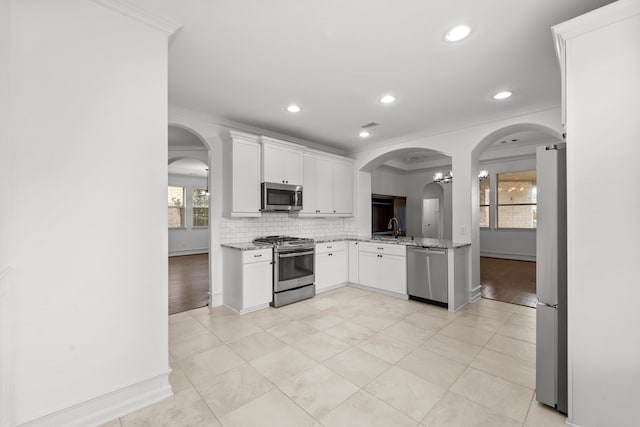 16746 Highland Country Dr, Cypress, TX 77433 - kitchen featuring appliances with stainless steel finishes, light stone countertops, ornamental molding, decorative backsplash, and white cabinetry