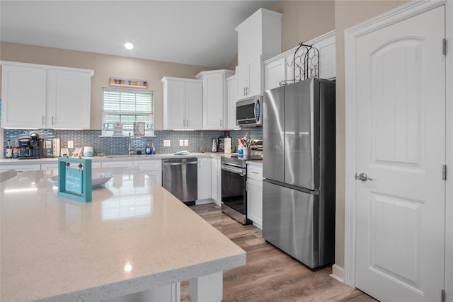 975 S S Cv, Crystal Beach, TX 77650 - kitchen featuring stainless steel appliances, tasteful backsplash, white cabinetry, light wood-style flooring, and light stone countertops