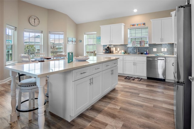 975 S S Cv, Crystal Beach, TX 77650 - kitchen with stainless steel appliances, vaulted ceiling, a kitchen island, light wood-style flooring, and plenty of natural light