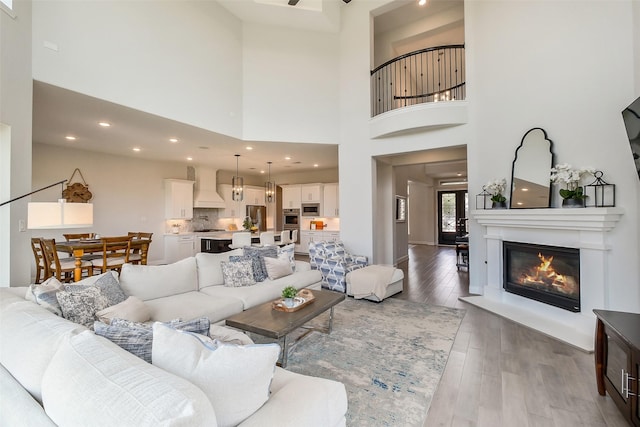 19506 Bradford Pines Ct, Cypress, TX 77433 - living room featuring wood finished floors, a high ceiling, a glass covered fireplace, and recessed lighting