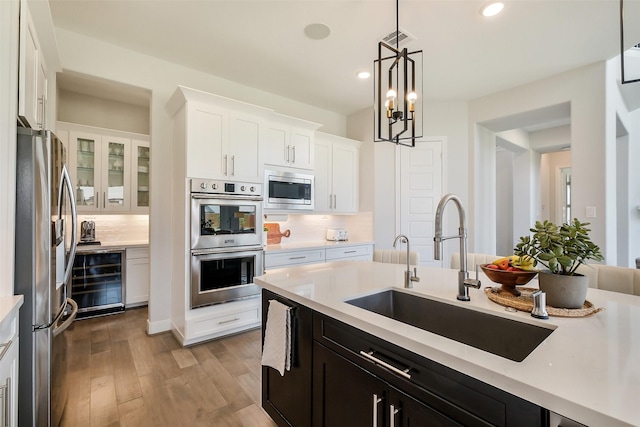 19506 Bradford Pines Ct, Cypress, TX 77433 - kitchen featuring appliances with stainless steel finishes, beverage cooler, light countertops, wood finished floors, and white cabinets