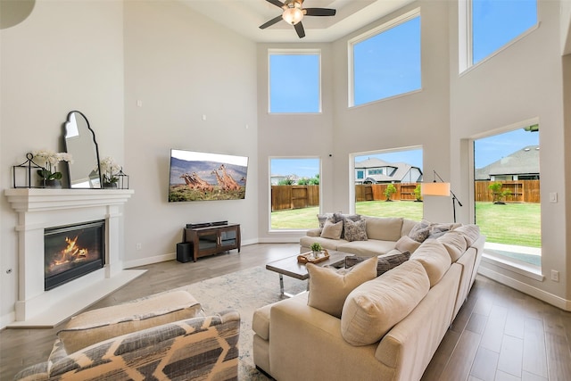 19506 Bradford Pines Ct, Cypress, TX 77433 - living area featuring a high ceiling, a ceiling fan, a glass covered fireplace, wood finished floors, and healthy amount of natural light