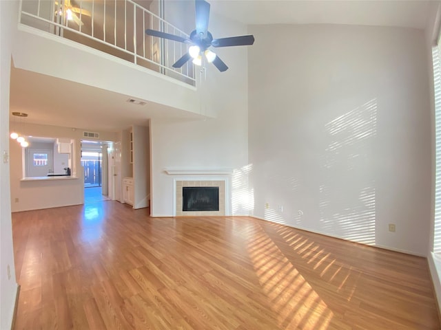 2601 S Braeswood Blvd Unit 605, Houston, TX 77025 - unfurnished living room featuring a fireplace, light wood-type flooring, a ceiling fan, and a towering ceiling