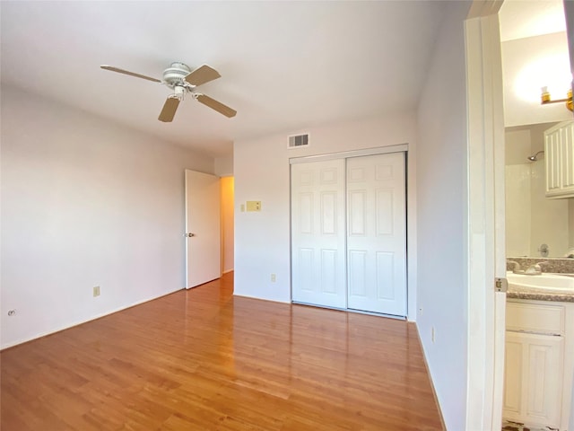 2601 S Braeswood Blvd Unit 605, Houston, TX 77025 - unfurnished bedroom with light wood-style flooring, a closet, connected bathroom, and ceiling fan