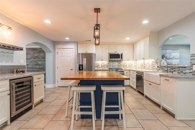 1017 Forest Rd, Clear Lake Shores, TX 77565 - kitchen featuring wine cooler, appliances with stainless steel finishes, backsplash, wood counters, and white cabinetry