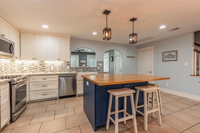 1017 Forest Rd, Clear Lake Shores, TX 77565 - kitchen featuring stainless steel appliances, butcher block countertops, arched walkways, light tile patterned flooring, and decorative backsplash