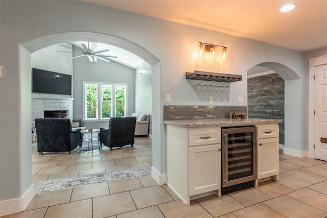 1017 Forest Rd, Clear Lake Shores, TX 77565 - indoor dry bar with wine cooler, a ceiling fan, light tile patterned flooring, a fireplace, and tasteful backsplash