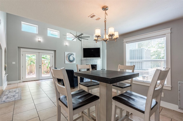 1017 Forest Rd, Clear Lake Shores, TX 77565 - dining area featuring a chandelier, light tile patterned floors, ceiling fan, a large fireplace, and french doors