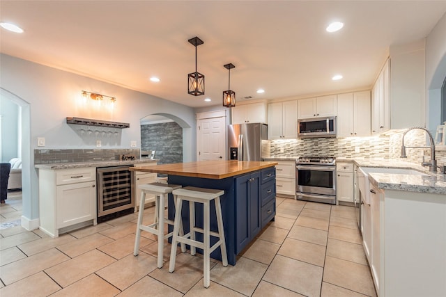 1017 Forest Rd, Clear Lake Shores, TX 77565 - kitchen featuring stainless steel appliances, wine cooler, butcher block counters, arched walkways, and backsplash