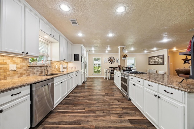 3214 Churchill St, Pearland, TX 77581 - kitchen with stainless steel appliances, a textured ceiling, dark wood-style floors, white cabinetry, and decorative backsplash