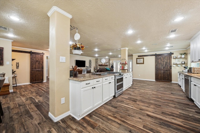 3214 Churchill St, Pearland, TX 77581 - kitchen featuring a barn door, a textured ceiling, stainless steel appliances, dark wood-style flooring, and crown molding