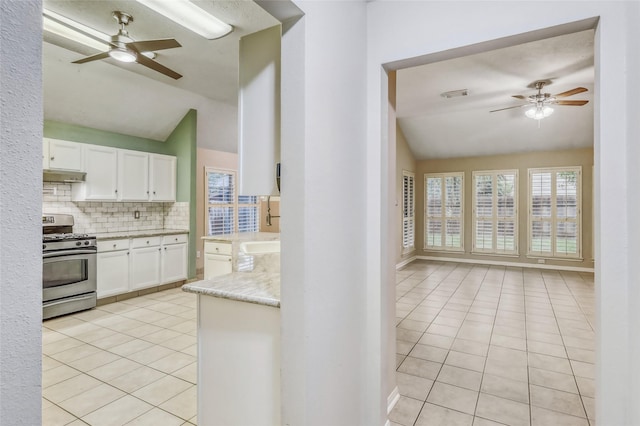 7215 Pembrough Ln, Katy, TX 77494 - kitchen with stainless steel gas range, vaulted ceiling, a ceiling fan, light tile patterned floors, and under cabinet range hood