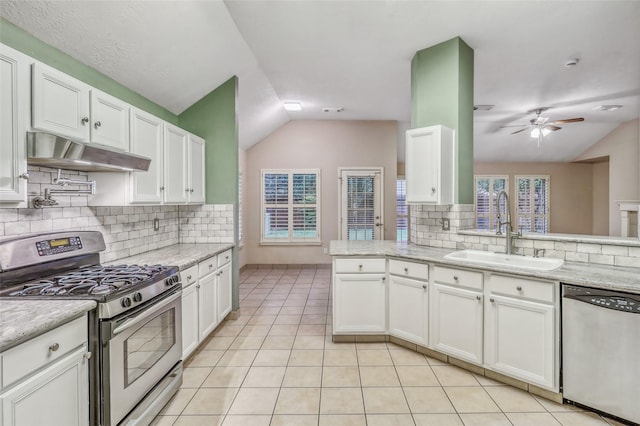 7215 Pembrough Ln, Katy, TX 77494 - kitchen featuring appliances with stainless steel finishes, under cabinet range hood, lofted ceiling, decorative backsplash, and light tile patterned floors
