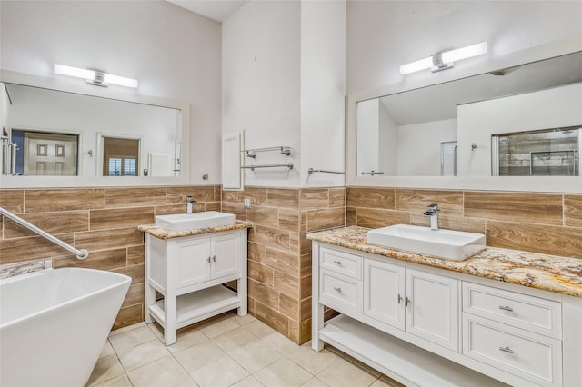 7215 Pembrough Ln, Katy, TX 77494 - full bath with tile walls, tile patterned floors, two vanities, a freestanding tub, and wainscoting