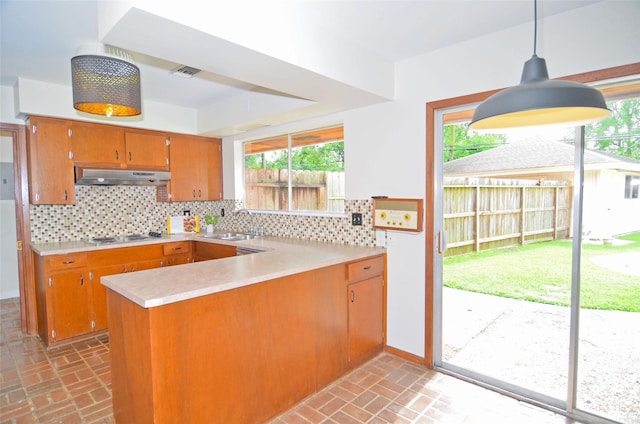 823 Timber Cove Dr, Seabrook, TX 77586 - kitchen with brick flooring, under cabinet range hood, brown cabinets, and a peninsula