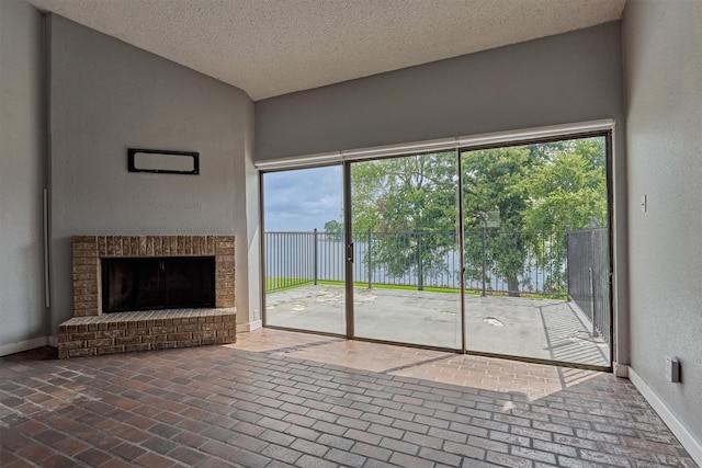 1437 Bowsprit Pt, Willis, TX 77318 - unfurnished living room with brick flooring, a textured ceiling, and a brick fireplace