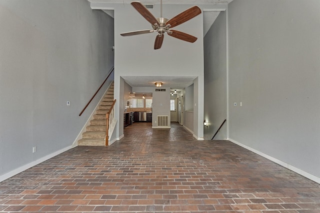 1437 Bowsprit Pt, Willis, TX 77318 - unfurnished living room featuring brick floors, high vaulted ceiling, a ceiling fan, and stairway