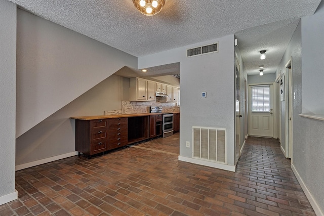 1437 Bowsprit Pt, Willis, TX 77318 - kitchen with stainless steel range with electric stovetop, brick flooring, a textured ceiling, light countertops, and under cabinet range hood