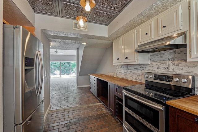 1437 Bowsprit Pt, Willis, TX 77318 - kitchen with stainless steel appliances, butcher block counters, under cabinet range hood, brick flooring, and a textured ceiling