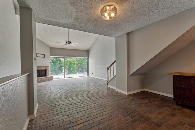 1437 Bowsprit Pt, Willis, TX 77318 - unfurnished living room with a textured ceiling, ceiling fan, brick flooring, a fireplace, and stairway
