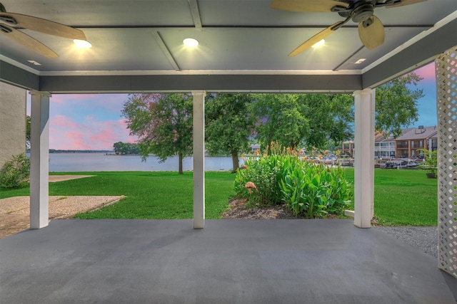 1437 Bowsprit Pt, Willis, TX 77318 - patio terrace at dusk with a water view, ceiling fan, a patio, and a lawn
