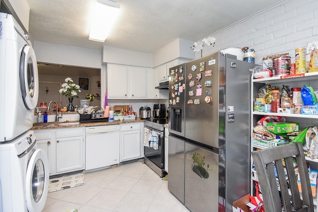 12469 Sharpview Dr Unit 2469, Houston, TX 77072 - kitchen with stainless steel appliances, stacked washer / dryer, under cabinet range hood, white cabinets, and a textured ceiling