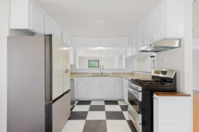 5426 Carew St, Houston, TX 77096 - kitchen featuring freestanding refrigerator, stainless steel range with gas cooktop, under cabinet range hood, and white cabinetry
