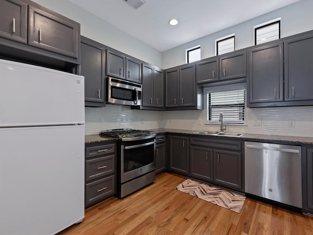 2710 Hullsmith Dr Unit 1004, Houston, TX 77063 - kitchen with appliances with stainless steel finishes, dark stone counters, backsplash, light wood-style flooring, and recessed lighting