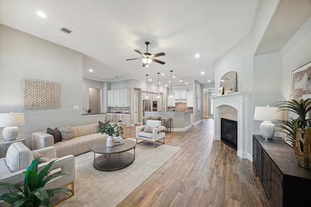 27722 Lakeway Trail Ln, Fulshear, TX 77441 - living room with a ceiling fan, wood finished floors, recessed lighting, and a glass covered fireplace