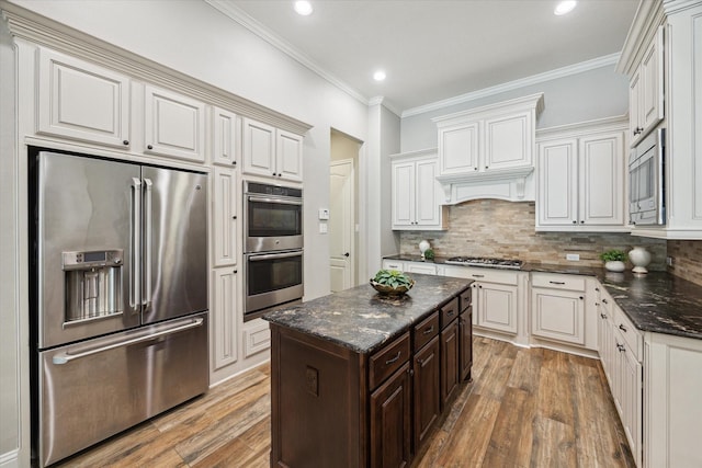 27722 Lakeway Trail Ln, Fulshear, TX 77441 - kitchen featuring appliances with stainless steel finishes, light wood-style floors, decorative backsplash, ornamental molding, and dark brown cabinetry