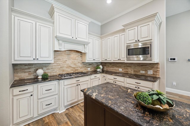 27722 Lakeway Trail Ln, Fulshear, TX 77441 - kitchen featuring appliances with stainless steel finishes, light wood finished floors, dark stone counters, decorative backsplash, and ornamental molding