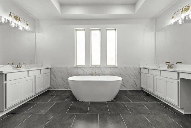 10922 Palmwood Dr, Missouri City, TX 77459 - bathroom with tile walls, a wainscoted wall, two vanities, a tray ceiling, and a soaking tub