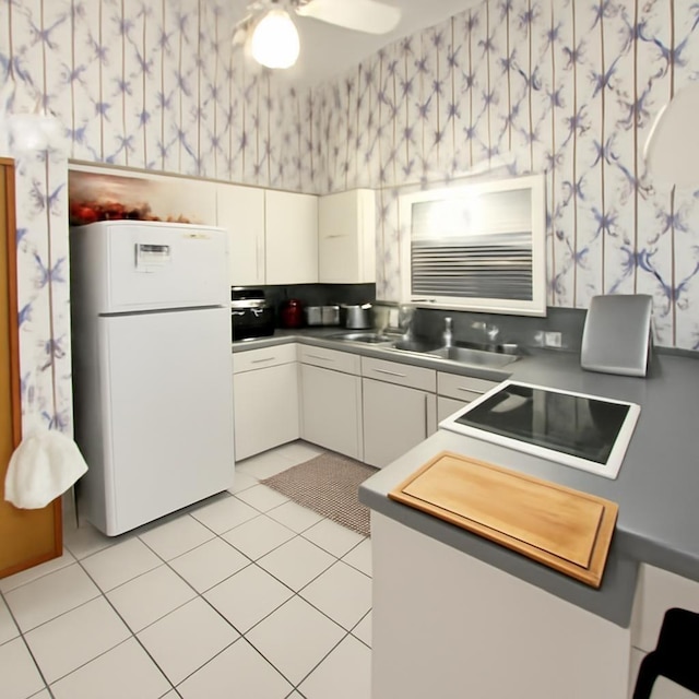 3185 Sea Castle Dr, Crystal Beach, TX 77650 - kitchen featuring freestanding refrigerator, wallpapered walls, black electric stovetop, light tile patterned floors, and white cabinets