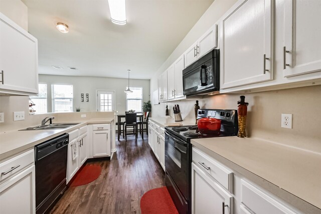 6103 Yorkglen Manor Ln, Houston, TX 77084 - kitchen with black appliances, dark wood finished floors, white cabinetry, light countertops, and a peninsula