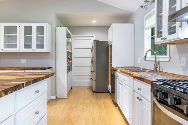 420 Hale St, Lexington, TX 78947 - kitchen with wooden counters, appliances with stainless steel finishes, light wood finished floors, wall chimney range hood, and white cabinetry
