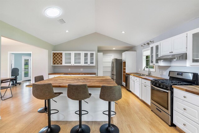 420 Hale St, Lexington, TX 78947 - kitchen with butcher block countertops, appliances with stainless steel finishes, under cabinet range hood, lofted ceiling, and white cabinetry