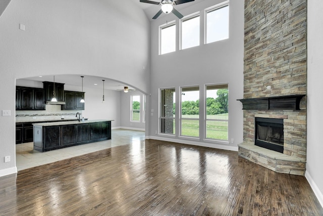 1708 Stillwater Dr, Burleson, TX 76028 - unfurnished living room with ceiling fan, light wood-type flooring, a towering ceiling, a fireplace, and healthy amount of natural light