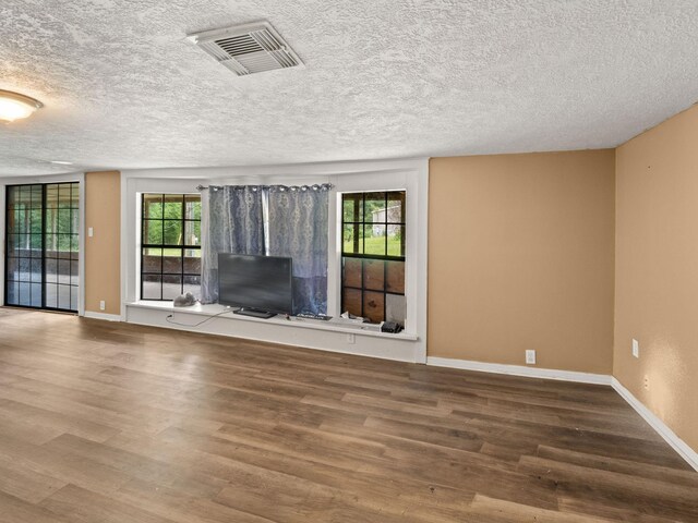 19995 Fm 92 S, Fred, TX 77616 - unfurnished living room with healthy amount of natural light, wood finished floors, and a textured ceiling