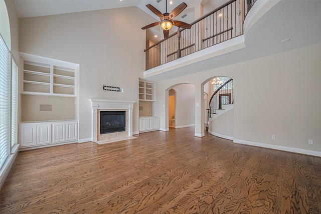 9 Foxworth Ct, Sugar Land, TX 77479 - unfurnished living room featuring built in shelves, arched walkways, wood finished floors, a ceiling fan, and stairs